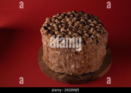 Fotografieren Sie Walnusskuchen auf einem Holzbrett auf rotem Hintergrund Stockfoto