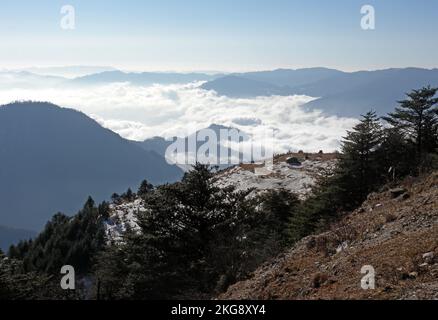 Genießen Sie den Blick auf verschneite Hänge am Morgen mit Wolken im Valley Eaglenest Wildlife Sanctuary, Arunachal Pradesh, Indien Januar Stockfoto