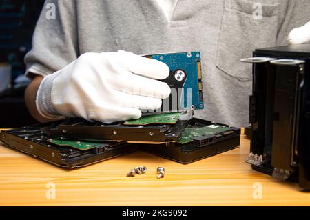 2,5-Zoll-Festplatten sind heute noch beliebt, da Techniker eine Festplatte in der Hand halten Stockfoto