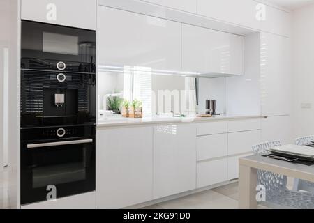 Weiße Küche mit Einbaugeräten in moderner Wohnung Stockfoto