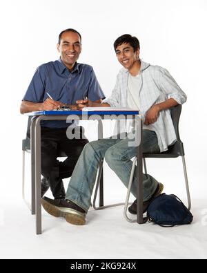 Teenager: Hauslehrer. Ein südasiatischer Lehrer und sein indischer Schüler lächeln. Aus einer Reihe von zugehörigen Bildern. Stockfoto