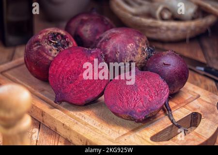 Rote Bete: Rote Bete auf einem Schneidebrett und eine in der Mitte, auf dem Tisch Stockfoto