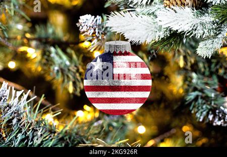 Neujahrs-Glaskugel mit der Flagge Liberias vor einem bunten Weihnachtshintergrund Stockfoto