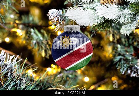 Neujahrsglass mit der Flagge Namibias vor einem bunten Weihnachtshintergrund Stockfoto