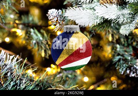 Neujahrsglass mit der Flagge der Seychellen vor einem bunten Weihnachtshintergrund Stockfoto