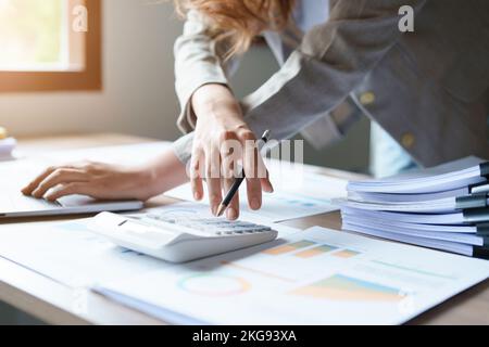 Buchhalter, asiatische Wirtschaftsprüfer verwenden Rechner und Computer, um die jährlichen Steuerbudgets zu überprüfen, um Informationen an das IRS zu übermitteln. Stockfoto