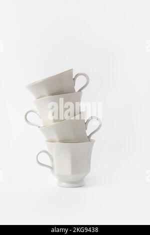 Stapel weißer Kaffeetassen mit goldenem Rand auf weißem Hintergrund Stockfoto