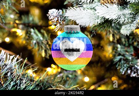 Neujahrs-Glaskugel mit der Flagge von Antisexual vor einem bunten weihnachtlichen Hintergrund Stockfoto