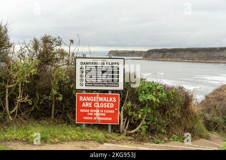 Ein Schild warnt vor gefährlichen Klippen und der Schließung eines Spaziergangs auf dem Schießstand in Kimmeridge Bay, Dorset, Großbritannien. Stockfoto