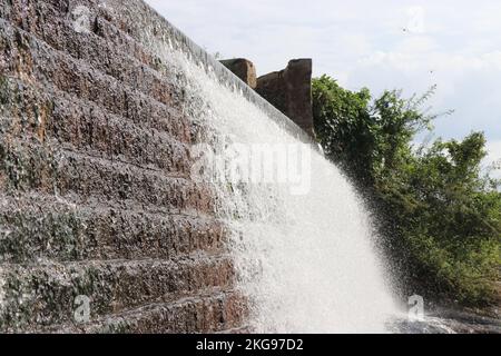 Wasser, das aus einem überfließenden Staudammbecken durch Ziegel fließt Stockfoto