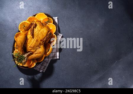 Weihnachtlich gebackenes Hähnchen oder truthahn mit Gewürzen, Orangen und Cranberries auf dunklem Betonhintergrund Kopierraum Draufsicht Stockfoto