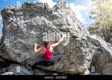 Beschreibung: Sportliche Frau klettert nachmittags auf einen Felsblock. Falzarego Pass, Dolomiten, Südtirol, Italien, Europa. Stockfoto