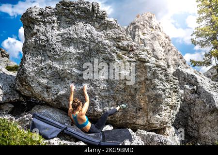 Beschreibung: Sportliche Frau klettert nachmittags auf einen Felsblock. Falzarego Pass, Dolomiten, Südtirol, Italien, Europa. Stockfoto