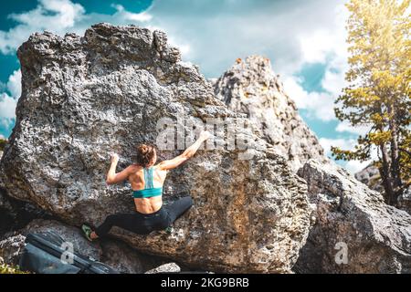 Beschreibung: Sportliche Frau klettert nachmittags auf einen Felsblock. Falzarego Pass, Dolomiten, Südtirol, Italien, Europa. Stockfoto