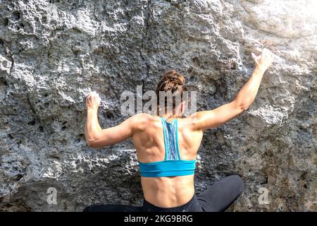 Beschreibung: Sportliche Frau klettert nachmittags auf einen Felsblock. Falzarego Pass, Dolomiten, Südtirol, Italien, Europa. Stockfoto