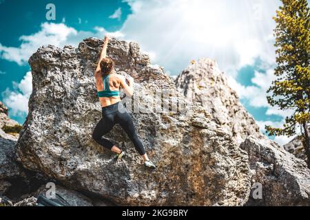 Beschreibung: Sportliche Frau klettert nachmittags auf einen Felsblock. Falzarego Pass, Dolomiten, Südtirol, Italien, Europa. Stockfoto