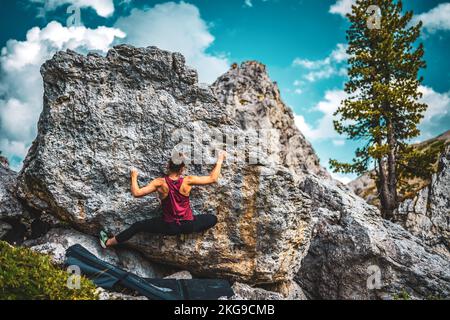 Beschreibung: Sportliche Frau klettert nachmittags auf einen Felsblock. Falzarego Pass, Dolomiten, Südtirol, Italien, Europa. Stockfoto