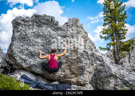 Beschreibung: Sportliche Frau klettert nachmittags auf einen Felsblock. Falzarego Pass, Dolomiten, Südtirol, Italien, Europa. Stockfoto