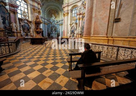 Rajhrad, Tschechische Republik - 22. Mai 2022: Benediktinermönch sitzt in der Kirche St. Peter und Paul und las die Heilige Bibel in Rajhrad, Tschechische Republik. Stockfoto