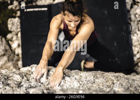 Beschreibung: Sportliche Frau klettert nachmittags auf einen Felsblock. Falzarego Pass, Dolomiten, Südtirol, Italien, Europa. Stockfoto