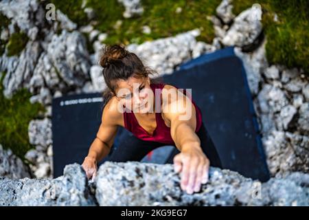 Beschreibung: Sportliche Frau klettert nachmittags auf einen Felsblock. Falzarego Pass, Dolomiten, Südtirol, Italien, Europa. Stockfoto