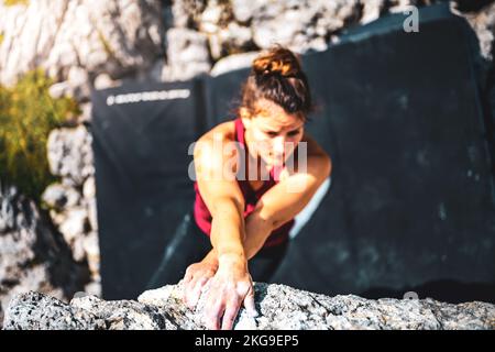 Beschreibung: Sportliche Frau klettert nachmittags auf einen Felsblock. Falzarego Pass, Dolomiten, Südtirol, Italien, Europa. Stockfoto