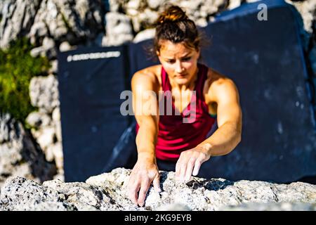 Beschreibung: Sportliche Frau klettert nachmittags auf einen Felsblock. Falzarego Pass, Dolomiten, Südtirol, Italien, Europa. Stockfoto