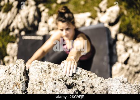 Beschreibung: Sportliche Frau klettert nachmittags auf einen Felsblock. Falzarego Pass, Dolomiten, Südtirol, Italien, Europa. Stockfoto