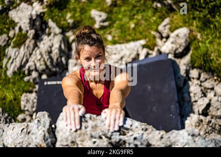Beschreibung: Sportliche Frau klettert nachmittags auf einen Felsblock. Falzarego Pass, Dolomiten, Südtirol, Italien, Europa. Stockfoto