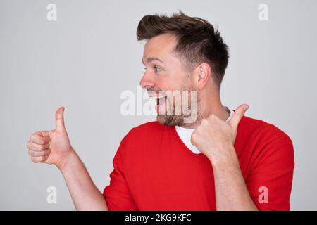 Attraktiver, fröhlicher junger Mann, der Daumen nach oben zeigt Stockfoto