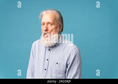 Porträt eines verblüfften grauen Bart Großvaters auf blauem Hintergrund mit Kopierbereich Stockfoto