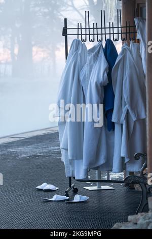 Bademäntel, Handtücher hängen an einem Kleiderständer, der draußen in der Nähe des Eingangs zum beheizten Winterpool steht Stockfoto