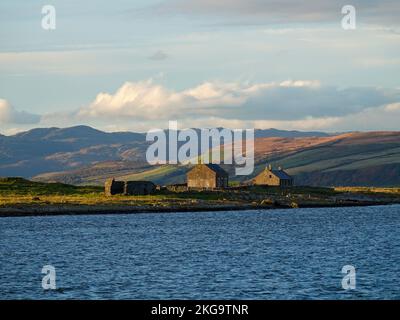 Landschaft mit Steinhütten der Fischer und Ruinen einer Kippering-Hütte an der Küste mit sanften Hügeln, St. Ninian's Bay, Argyll und Bute, Schottland, Vereinigtes Königreich. Stockfoto