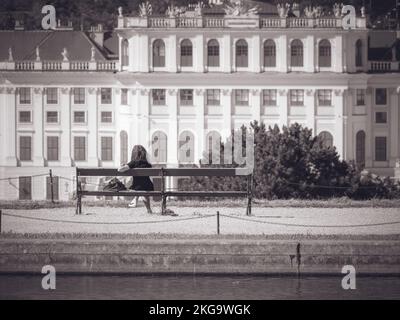 Rückblick mit einem Mädchen, das auf einer Bank in den Gärten des Schlosses Schönbrunn in Wien sitzt. Schwarz-weiße Straßenfotografie. Stockfoto