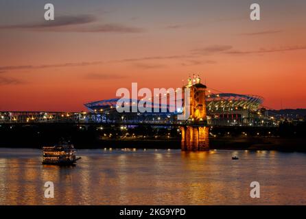 John A Roebling Hängebrücke in der Dämmerung. Paul Brown Stadium, Paycor Stadium, Heimstadion der Fußballmannschaft Cincinnati Bengals, im Hintergrund. Belle Stockfoto