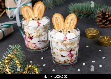 Kuchen ohne Backen in Form von süßen Kaninchen in Gläsern mit Kirschen, Keksen und Quark. Symbol für das neue Jahr 2023 Stockfoto