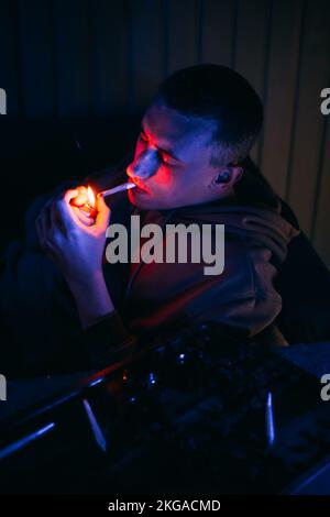 Porträt eines Mannes in Neon, der einen Joint raucht. Guy raucht Joint, Marihuana, Drogen cbd und thc Stockfoto