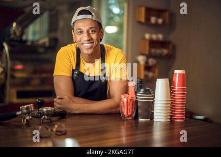 Lächelnder, zufriedener junger Barista in einem Café Stockfoto