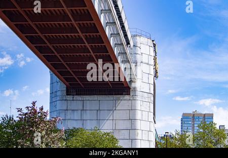 Technische Konstruktion der U-Bahn-Brücke mit Betonstützen, Ansicht von unten. Panorama der Stadt mit Himmel und Bäumen Stockfoto