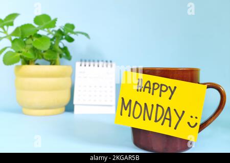 Willkommen, hallo und Happy Monday Concept. Selektiver Fokus der Kaffeetasse mit hellgelbem Zettel und schriftlicher Nachricht. Stockfoto