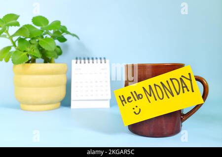 Willkommen, hallo und Happy Monday Concept. Selektiver Fokus der Kaffeetasse mit hellgelbem Zettel und schriftlicher Nachricht. Stockfoto