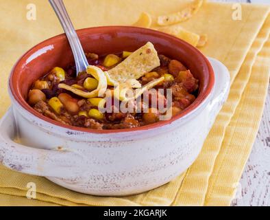 Nahaufnahme einer Schüssel Chili con Carne, garniert mit Maischips. Stockfoto