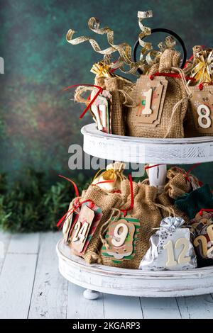 Ein hausgemachter Adventskalender auf einem zweistufigen rustikalen Holzständer. Stockfoto