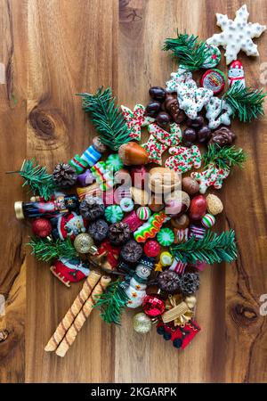 Festliche Süßigkeiten und Ornamente in Form eines Baumes auf einem Holzbrett. Stockfoto