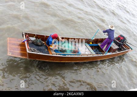 Asiatische Fischer segeln auf einem Boot und werfen ihre Netze ins Wasser Stockfoto