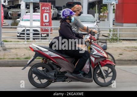 BANGKOK, THAILAND, JUNI 15 2022, Eine Frau mit Gesichtsmaske fährt auf einem Motorrad auf der Straße der Stadt Stockfoto