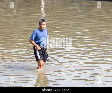 SAMUT PRAKAN, THAILAND, Okt 29 2022, Ein Mann läuft im Wasser auf einer überfluteten Straße Stockfoto