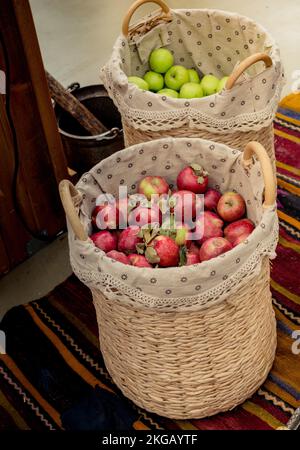 Rote und grüne Äpfel im Stroh Körbe in der Anzeige Stockfoto