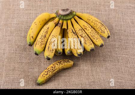 Ein Haufen gelber Sommersprossen-Bananen auf einer Leinwandstruktur Stockfoto