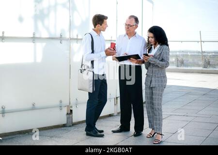 Ein reifer Geschäftsmann diskutiert einen neuen Vertrag mit jungen Kollegen. Stockfoto